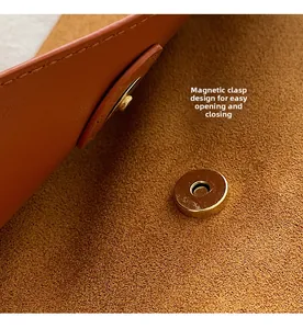 Détail de la boucle magnétique sur sac en daim marron avec coutures soignées