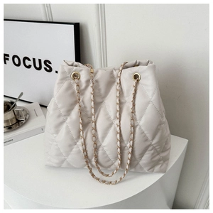 Close-up of beige quilted tote bag with diamond stitching and golden chain straps