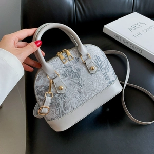 Detailed embroidery texture and golden zipper on grey seashell bag shown in close-up view