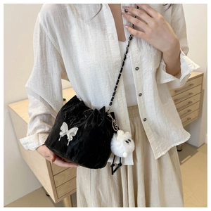 Détail du sac seau noir plissé avec papillon blanc et breloque en peluche douce