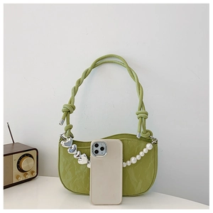 Detail of green ruched leather bag featuring silver heart charm and pearl chain accent