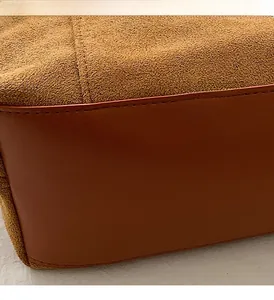 Gros plan des coutures précises sur le daim et le cuir lisse d'un grand sac cabas