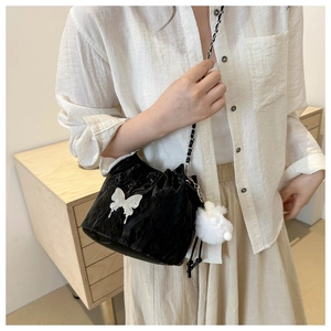 Détail du sac seau noir à cordon avec ornement papillon blanc et pompon en peluche doux