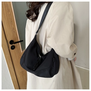 Detail of black waterproof nylon shoulder bag with moon shape and silver zipper toggle