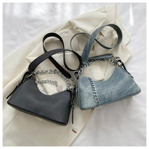 Detail of blue denim crescent bag with wide shoulder strap and chunky silver chain