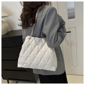 Vue détaillée du sac cabas matelassé blanc avec chaîne dorée sur l'épaule d'un modèle