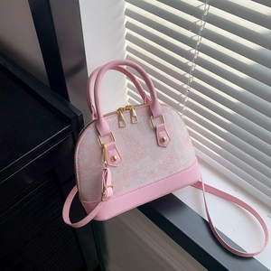 Close-up of pink shell-shaped bag featuring floral jacquard fabric and golden hardware