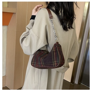 Detail of checkered shoulder bag with wool fabric and leather strap in street style