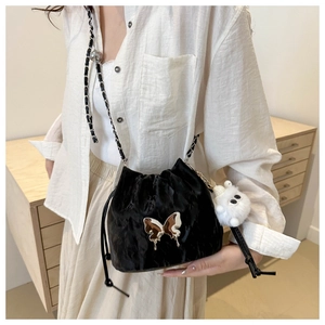 Gros plan du sac seau en satin noir avec papillon argenté et petit pendentif en peluche