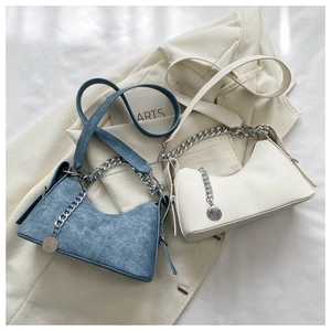 Detail of blue denim and white leather crescent bags with silver chain and pendant decoration
