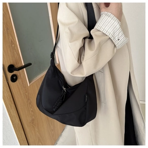 Close-up of black Oxford cloth crossbody bag featuring a SPORT tag and adjustable strap
