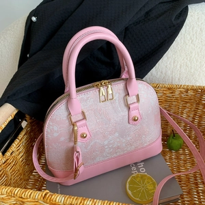 Detailed close-up of shell bag featuring pink leather and white jacquard embroidery