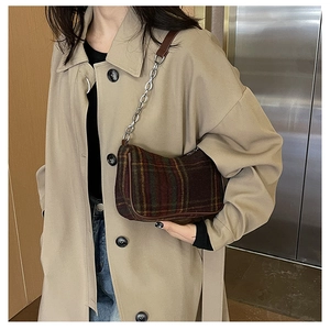 Detail of vintage plaid underarm bag with metal chain strap on model shoulder