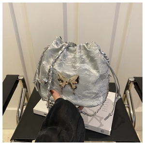 Détail du sac seau argenté plissé avec boucle papillon et bandoulière en chaîne