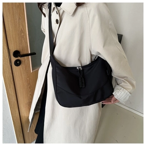 Detail of adjustable strap and zipper on a black waterproof nylon crossbody tote bag