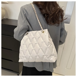 Detail of white quilted bucket bag with gold chain strap worn by a model