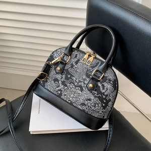 Elegant black shell crossbody bag with white wave print and golden hardware on a pedestal