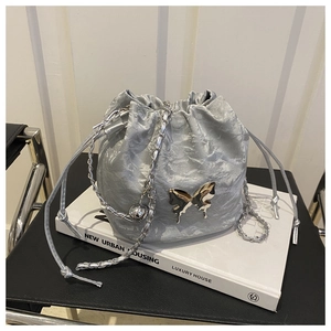Détail du sac seau argenté à cordon avec noeud métallique et bandoulière chaîne