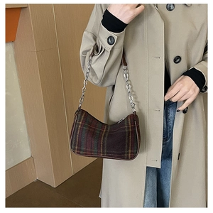 Detail of vintage tartan underarm bag with silver chain strap on a khaki trench coat
