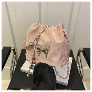 Détail d'un sac seau rose avec pendentif papillon métallique et bandoulière chaîne