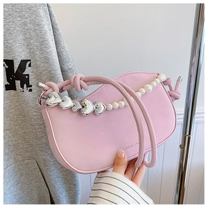 Detail of pink half-moon bag with elegant pearl chain and silver heart charm pendant