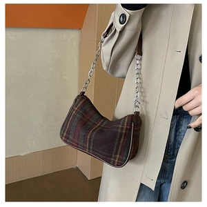 Detail of purple and green plaid underarm bag with silver chain strap on model shoulder