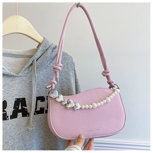 Detailed shot of pink leather underarm bag with silver hearts and pearl chain decoration