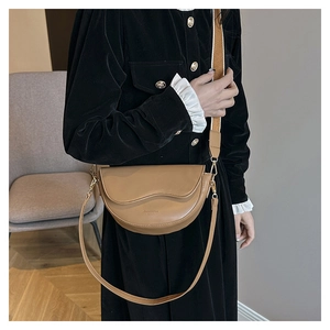 Detail of light brown saddle bag with wavy flap and dual interchangeable shoulder straps
