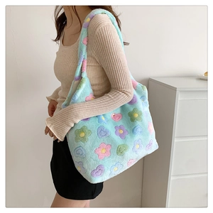 Detail of light blue plush tote bag with colorful floral patterns on a side-worn model