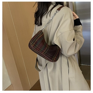 Detailed view of a retro plaid tweed underarm bag with silver chain strap on a model