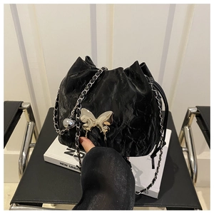 Détail du sac seau plissé noir avec boucle papillon argentée et bandoulière en chaîne