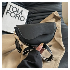 Detail of black leather saddle bag with wide shoulder strap and gold-tone metal hardware