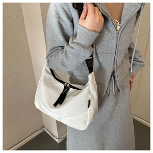 Detailed view of lightweight white nylon crescent bag with black strap and zipper knot
