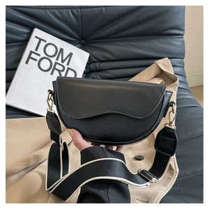 Detail of black semi-circle crossbody bag with wide canvas strap and gold hardware