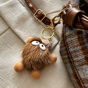 Detail of furry monster bag charm with knit hat on vintage plaid wool bucket bag