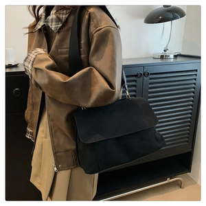 Détail du sac bandoulière noir en suédine avec large bandoulière et rabat moderne