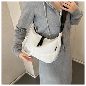 Minimalist white nylon hobo bag featuring wide black adjustable strap on female model