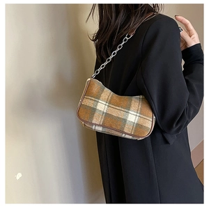 Detail of vintage plaid hobo bag with silver chain strap on a model wearing black
