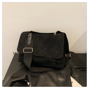 Détail du sac bandoulière en daim noir avec boucle dorée et large sangle réglable
