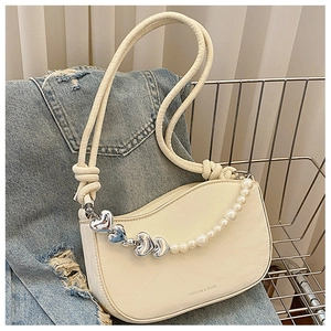 Close-up of cream white crescent bag with pearl heart chain and knot strap detail
