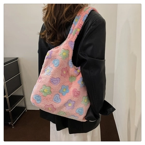 Plush pink tote bag with colorful floral jacquard pattern worn by a model in black leather jacket