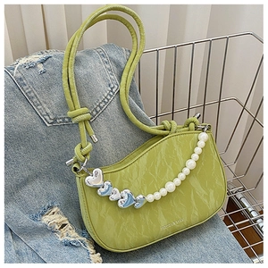 Detail of avocado green leather bag with pearl heart chain and pleated texture finish