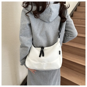 Detailed view of white waterproof nylon tote with sport label and black shoulder strap