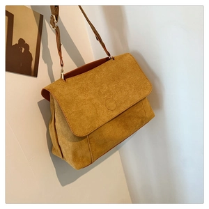 Détail du sac bandoulière en velours jaune avec grand rabat et boucle dorée ajustable