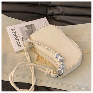 Detail of beige crescent shoulder bag with pearl heart chain and knotted strap design