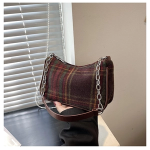 Close-up of vintage tartan underarm bag with metal chain and faux leather strap details