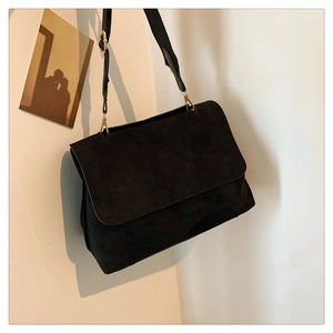 Détail du sac bandoulière en daim mat noir avec ferrures dorées et sangle large