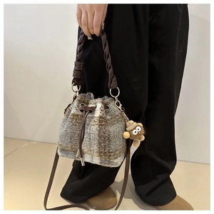 Detail of wool plaid bucket bag featuring woven handle and cute brown bear pendant