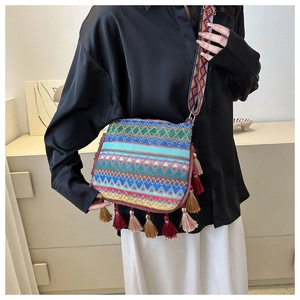 Close-up of bohemian woven crossbody bag with colorful tassels and patterned wide strap