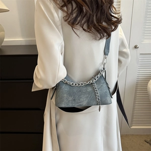 Gray washed denim crescent hobo bag with silver chain strap shown on a female model